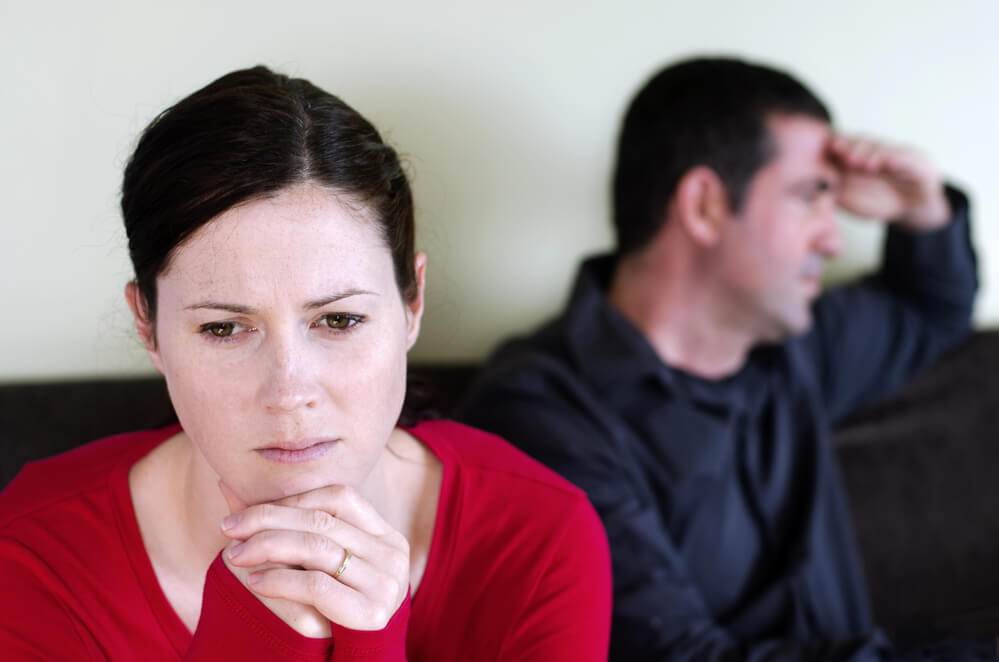 young white couple sitting apart and upset after being triggered into anger and now the fallout